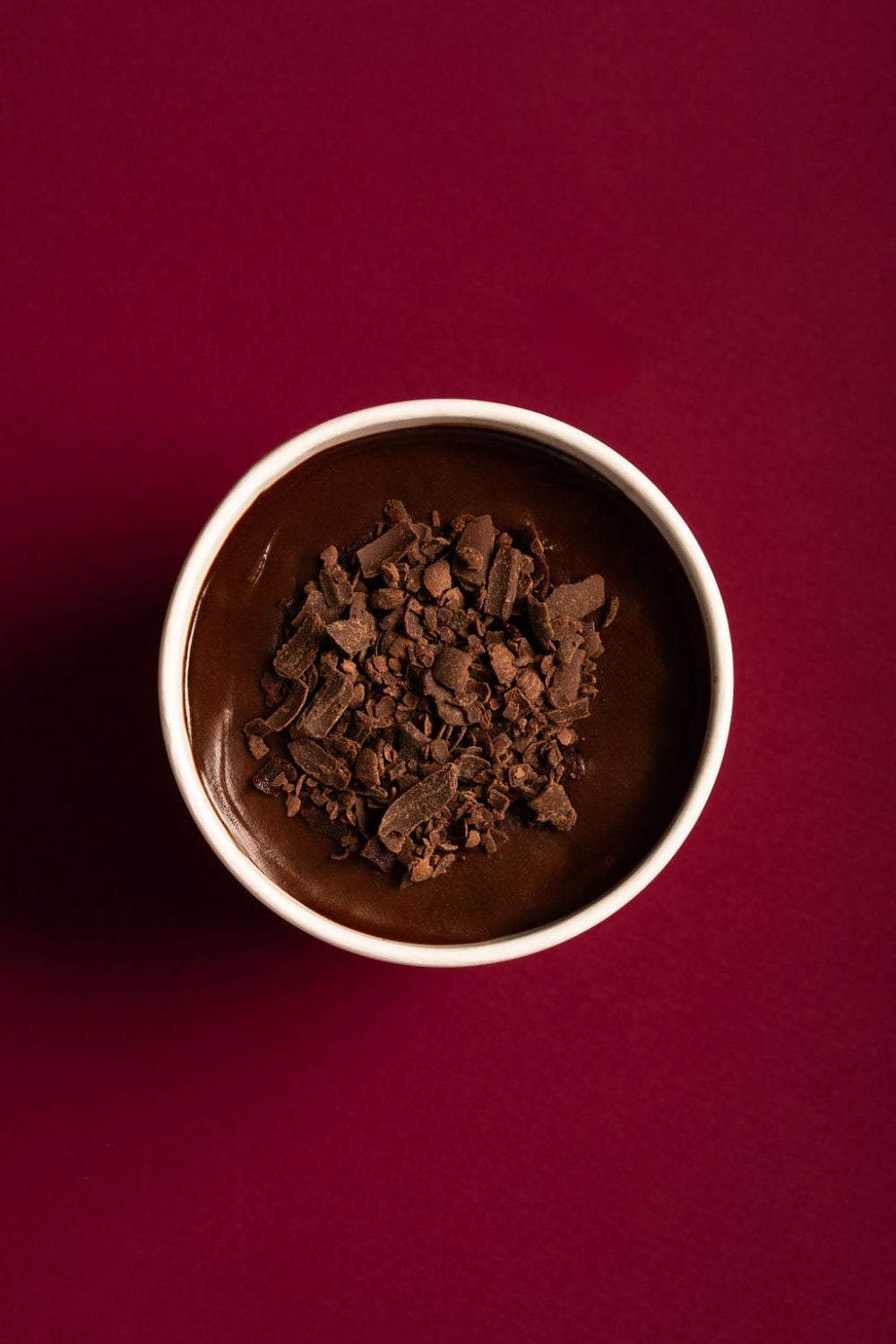 Cuchareable de torta de chocolate dentro de un contenedor de cartón. Una cuchara sostiene un pedazo del mismo postre.