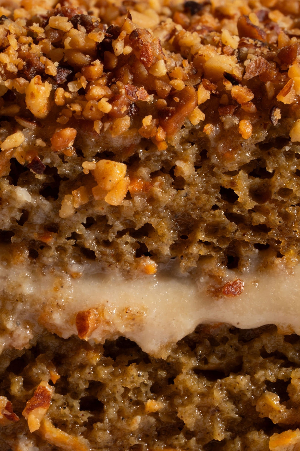 Cuchareable de torta de zanahoria dentro de un contenedor de cartón. Una cuchara sobre el postre sostiene un pedazo del mismo.