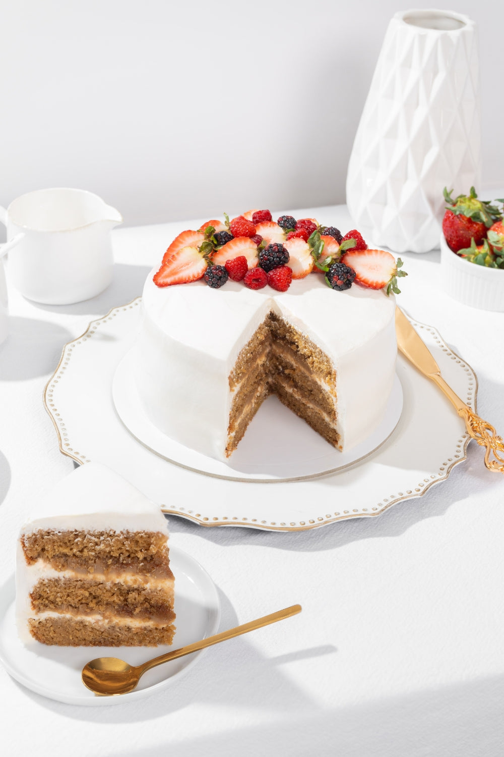 Torta de almendras partido sobre un plato. A su lado se encuentra un trozo de la torta con una cuchara a su lado.