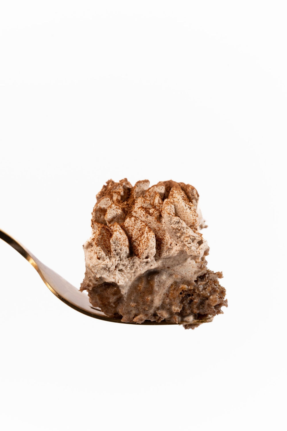 Una cuchara sujeta un pedazo de torta tres leches de chocolate.