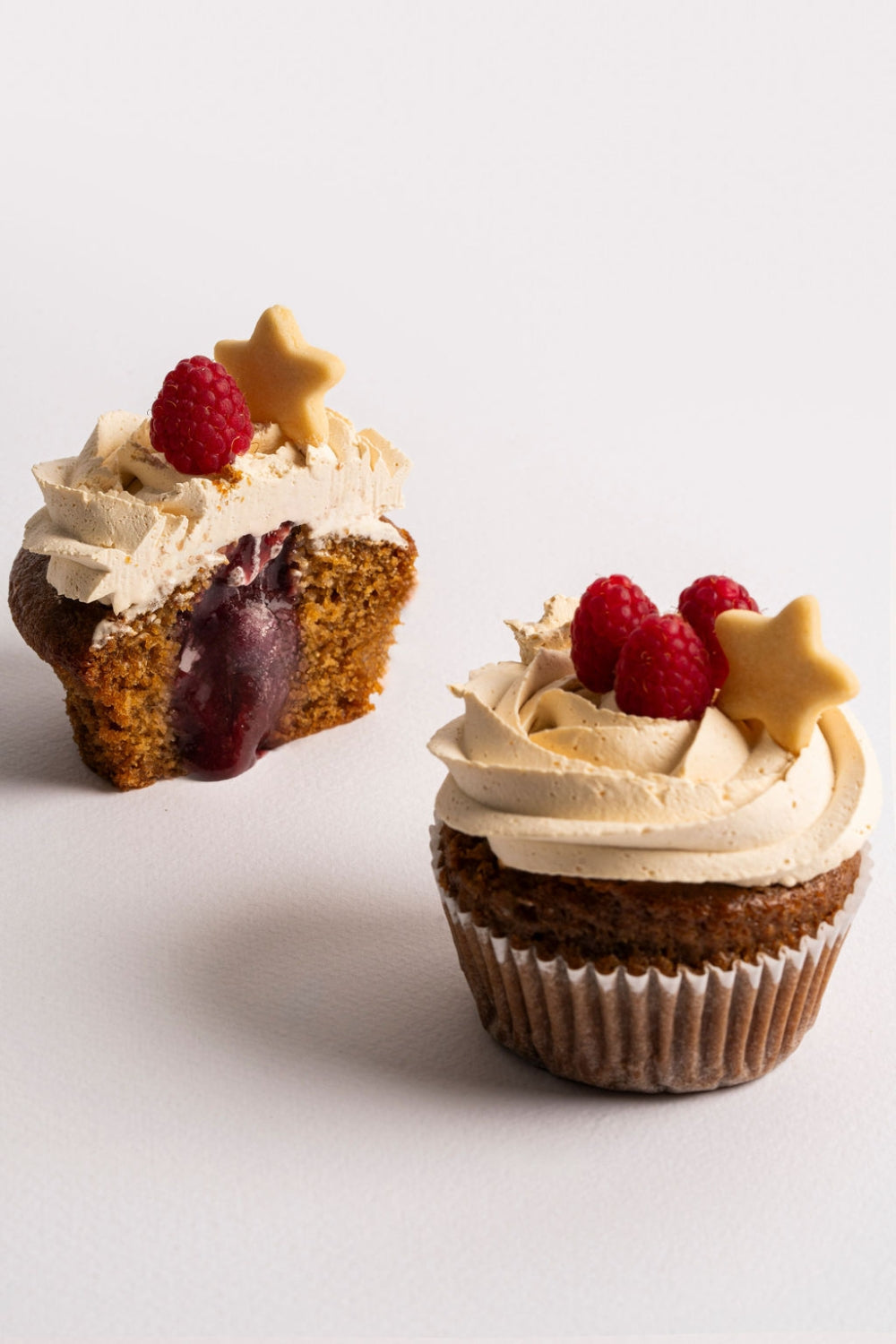 Dos cupcakes de berries. Uno está partido a la mitad y el relleno líquido de chorrea.