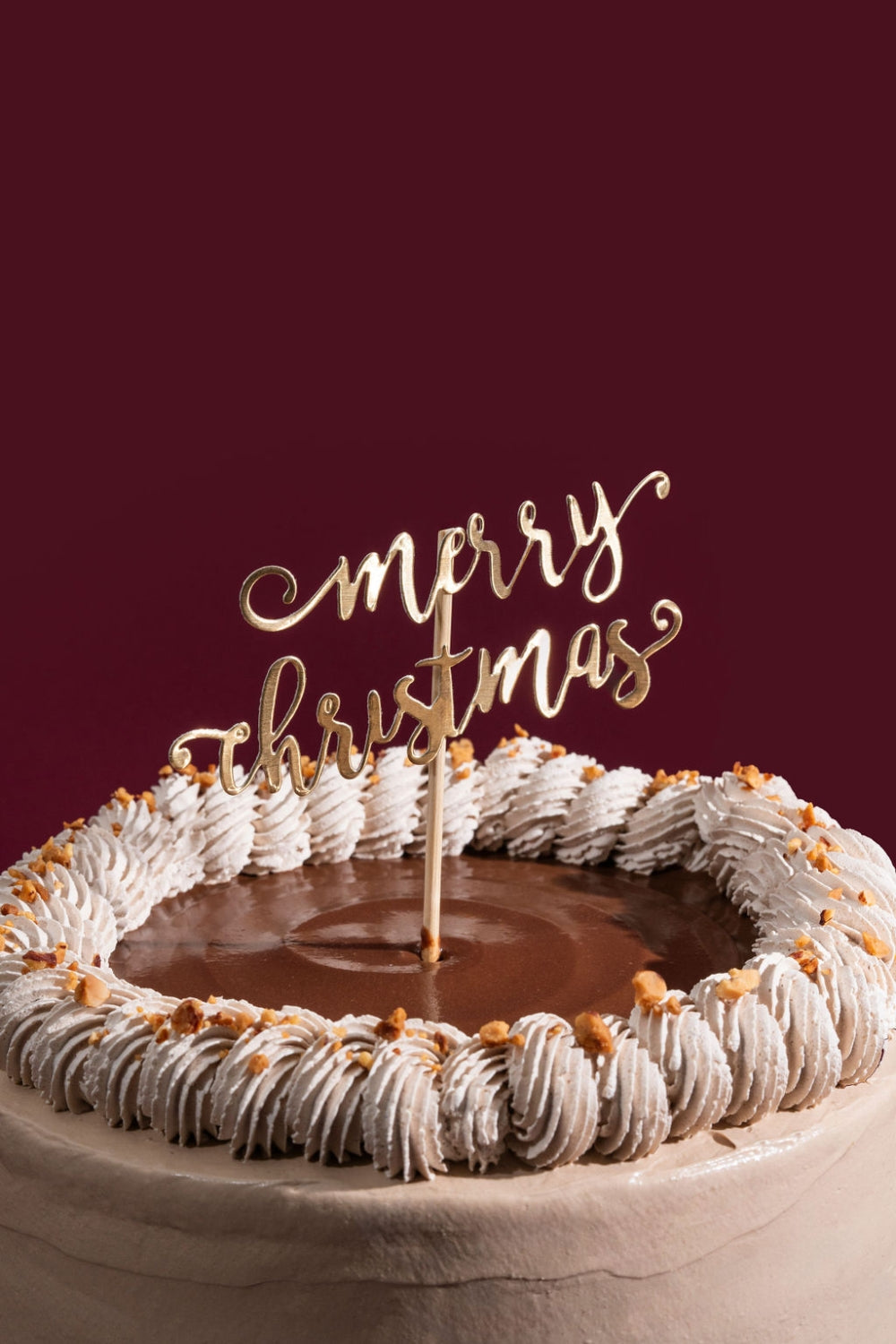 Acercamiento de una torta de moka. Sobre ella se encuentra un topper que dice "merry christmas".