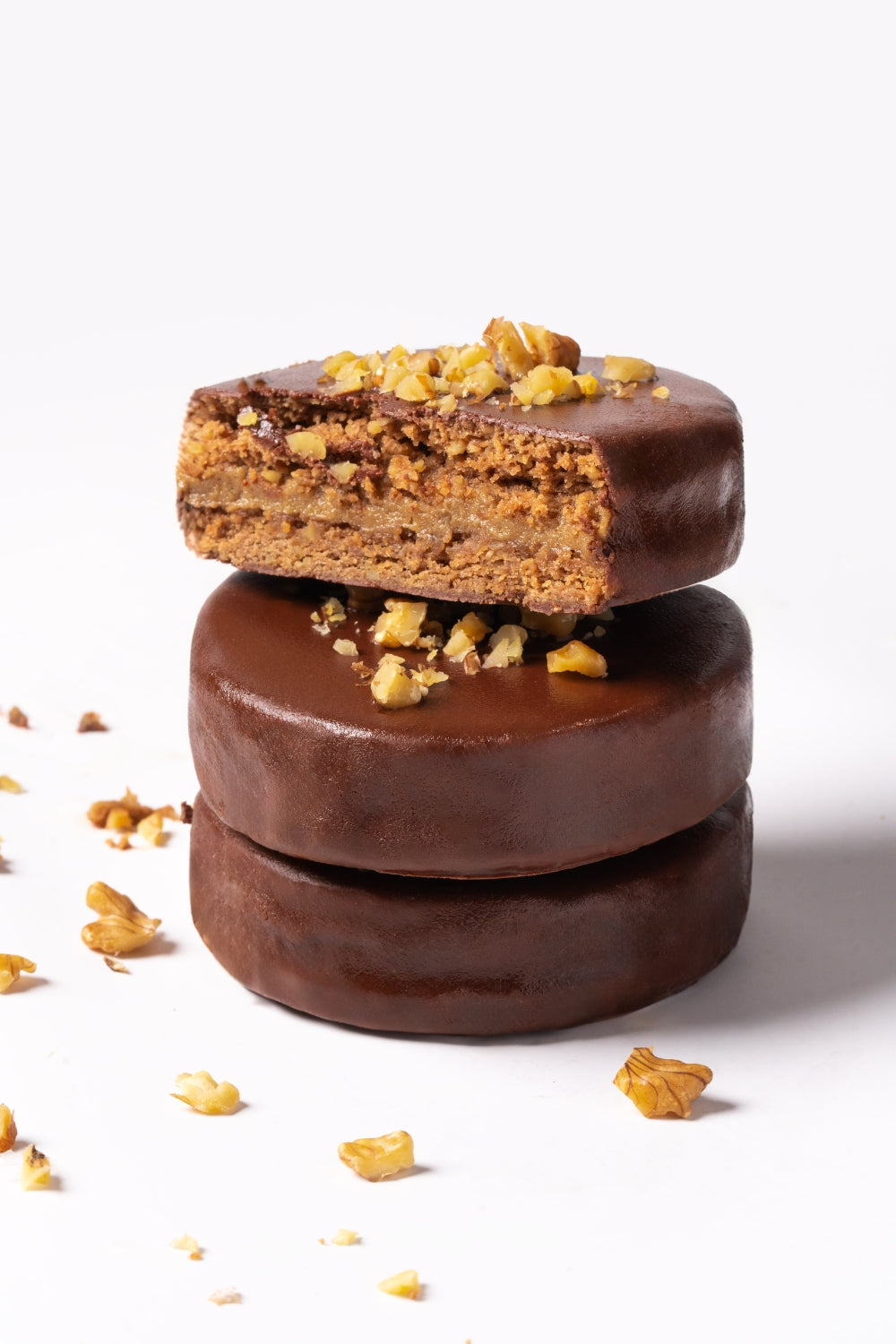 Tres alfajores de nueces apilados. El de encima está partido a la mitad. 