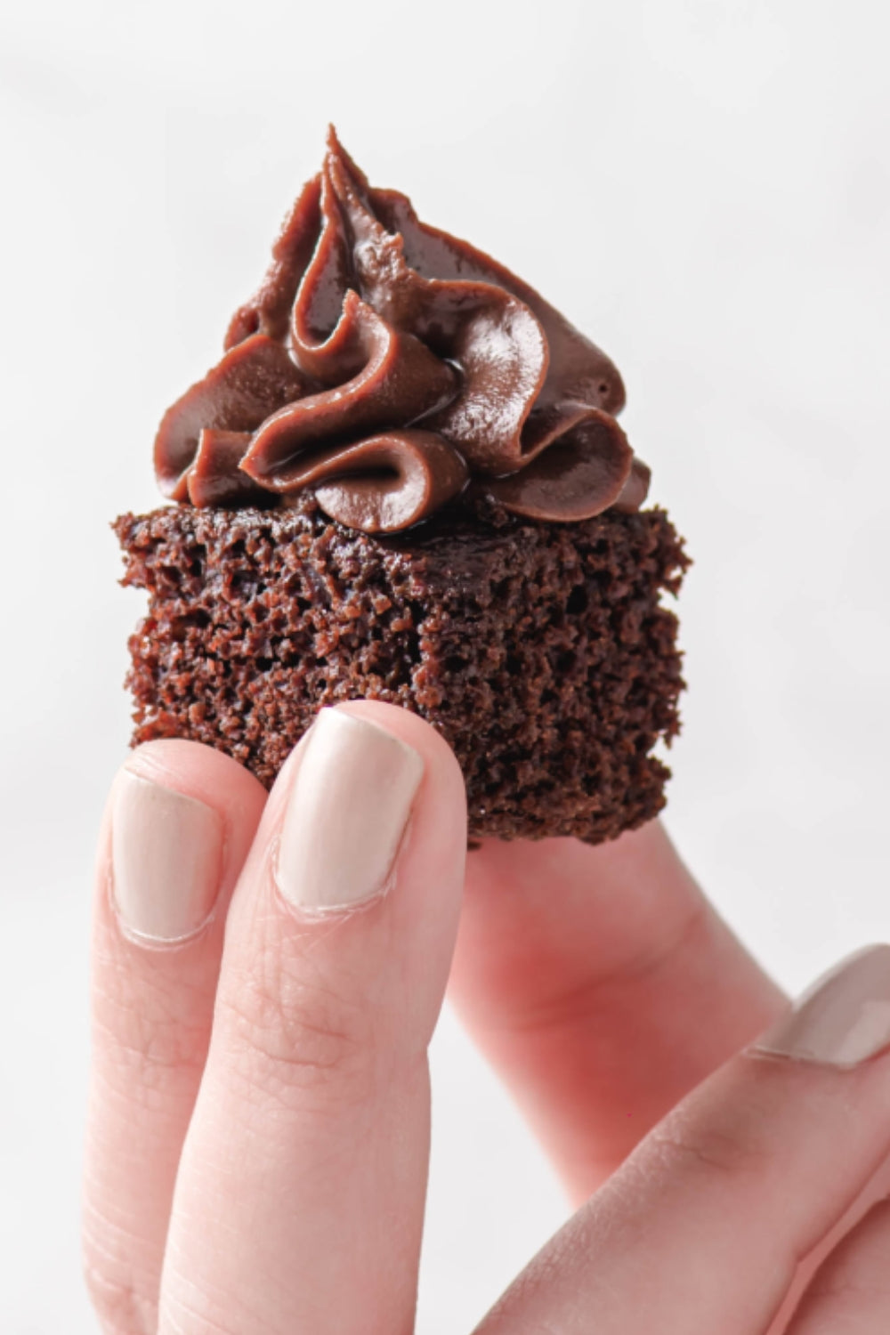 Una mano sujeta un bite de torta de chocolate. 