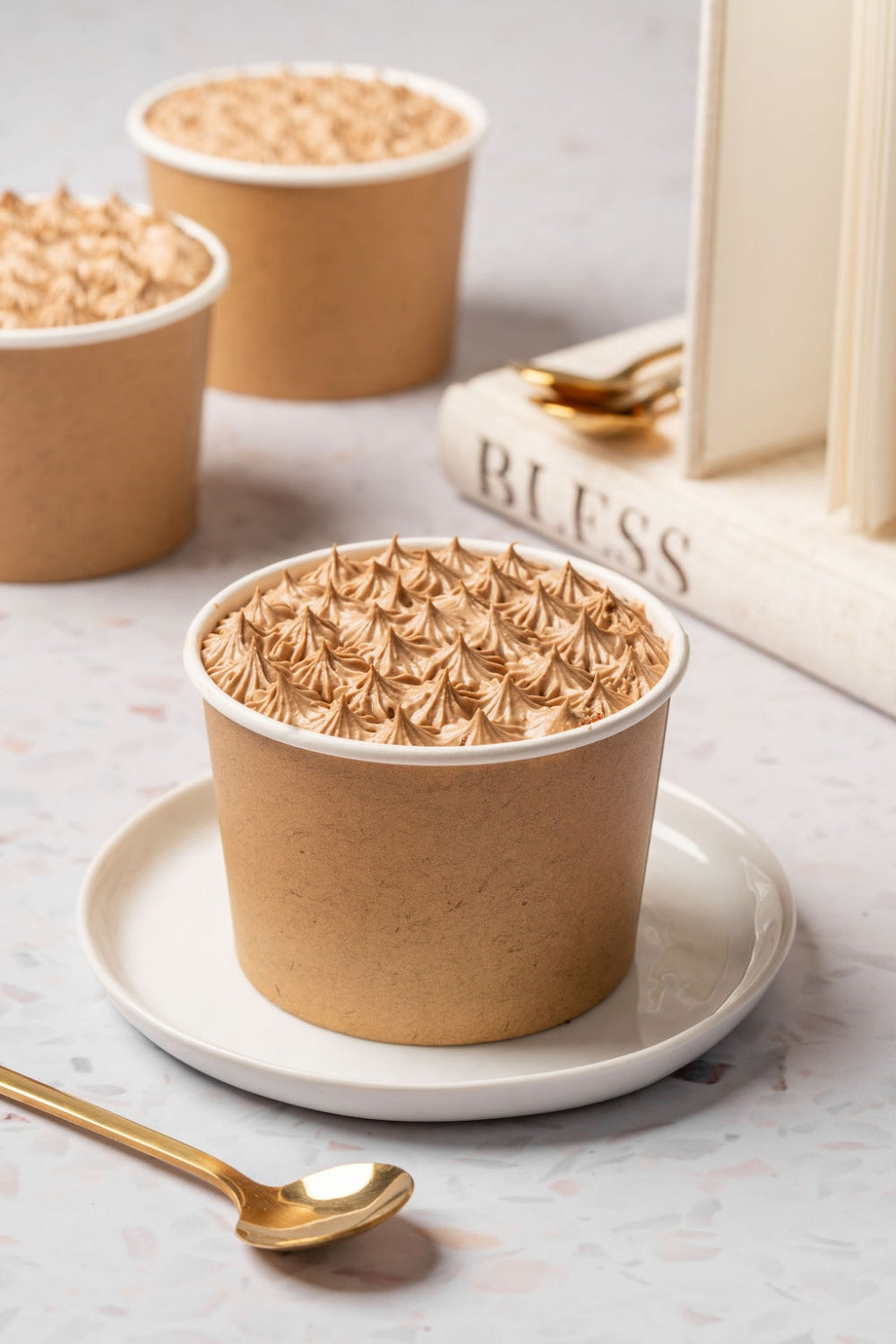 Cuchareable de torta de moka dentro de un contenedor de cartón. Una cuchara sostiene un pedazo del mismo postre. 