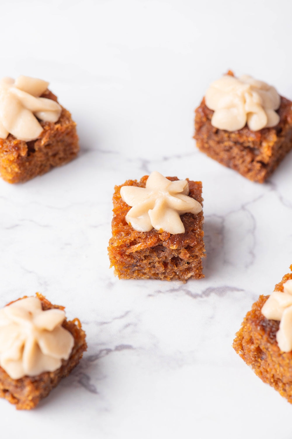 Mini bites de carrot cake sobre una superficie de marmol.
