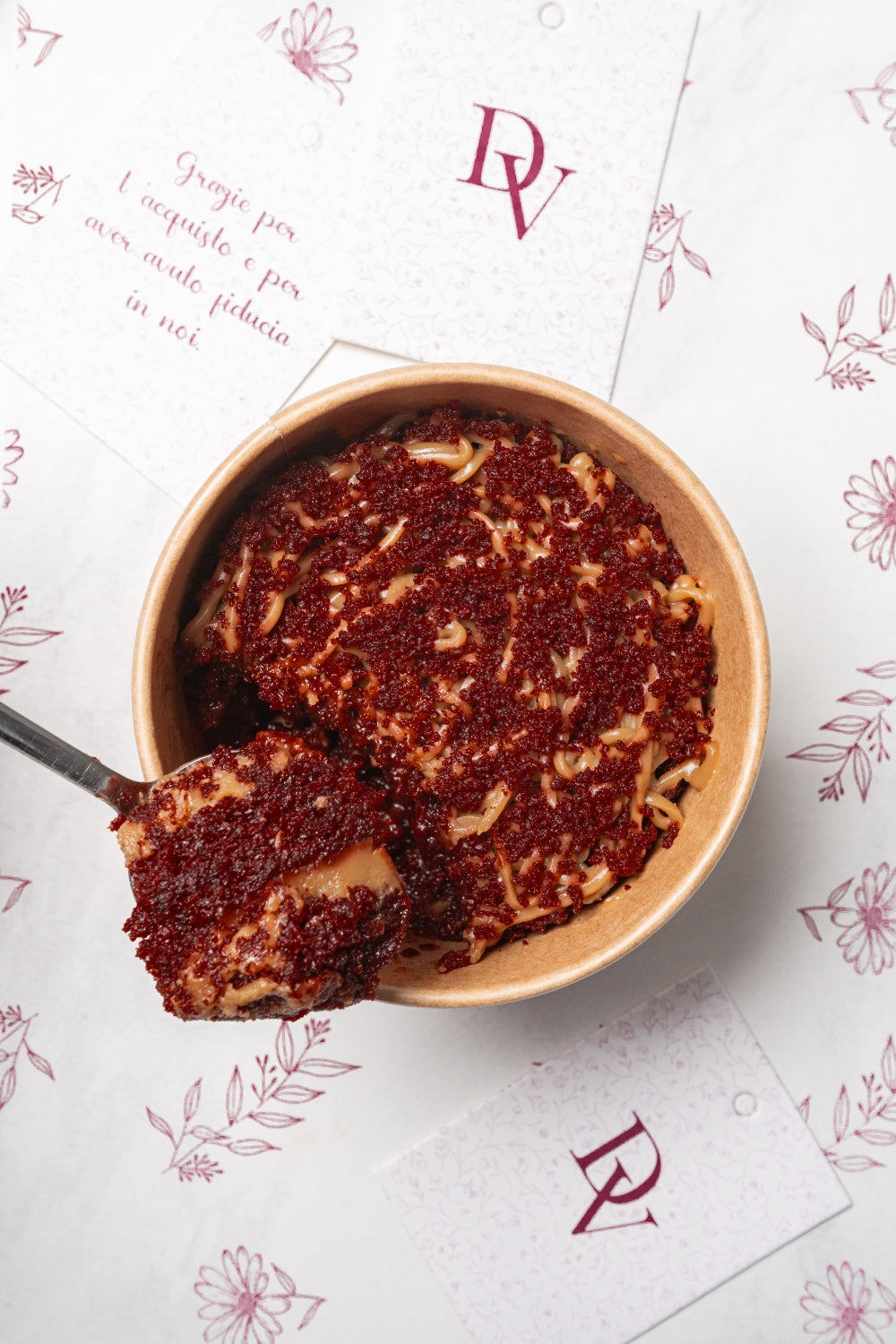 Cuchareable de red velvet. Una cuchara sostiene un pedazo del postre. 