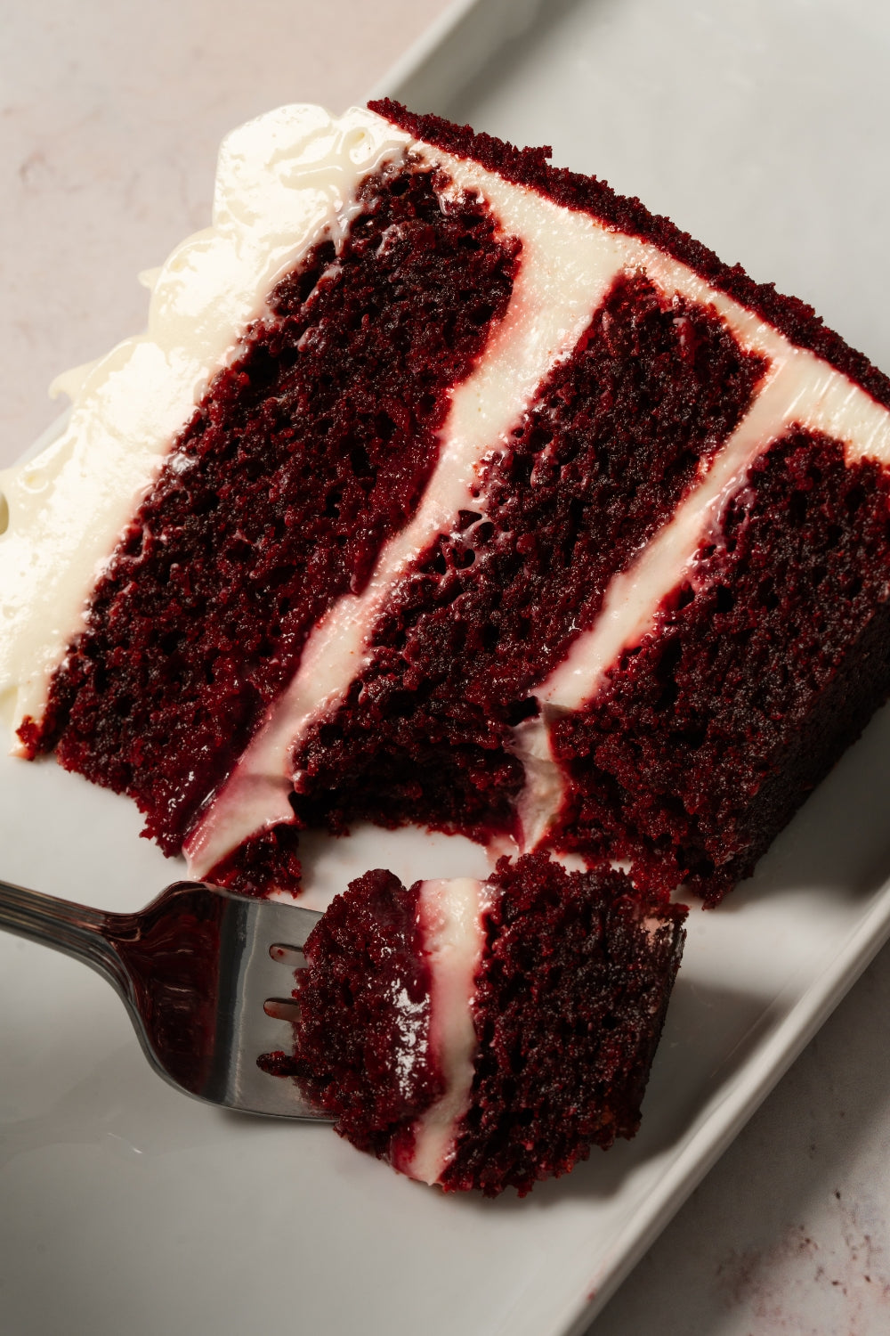Un trozo de torta red velvet. Un tenedor sostiene un pedazo del postre. 